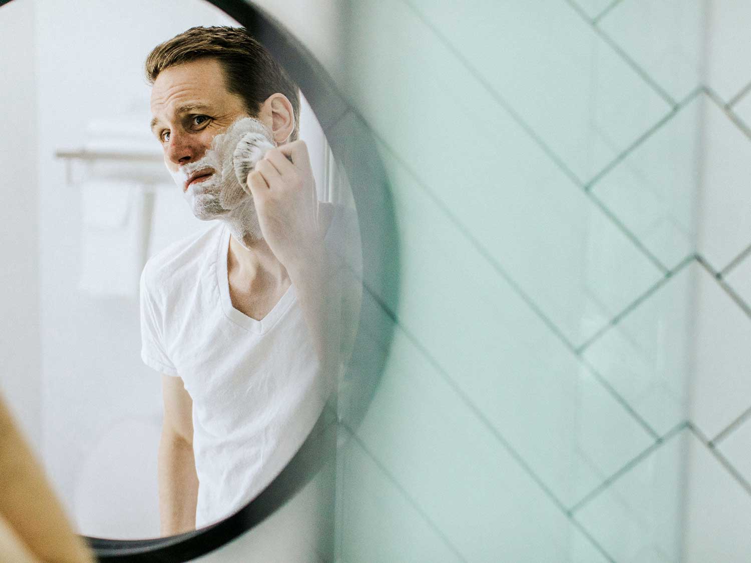 Man shaving in front of a mirror.