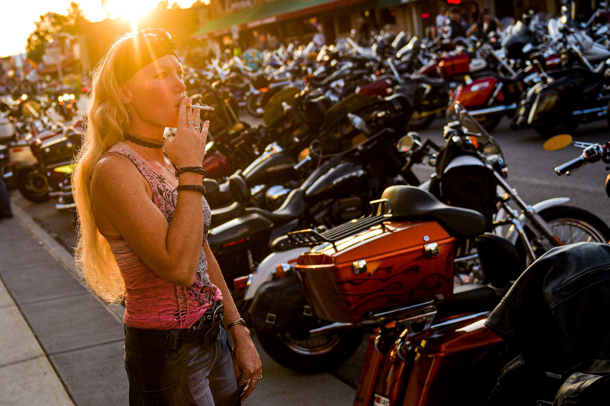 Landa Rehfeld smokes while taking in a motorcycle-packed Main Street in downtown Sturgis.