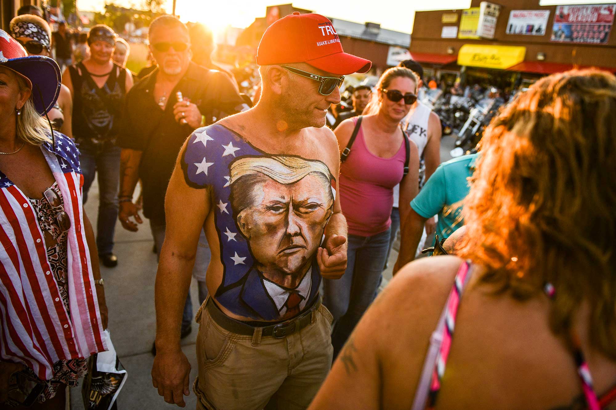 Johne Riley walks down Main Street showing off his chest painted with a portrait of President Trump.
